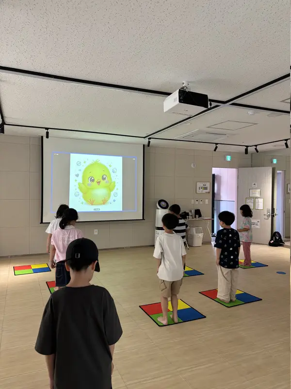 캐릭터 화면을 보며 4색 패드 위에서 참여하는 아동들